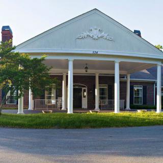 A classic building with white columns and a porch at the entrance.