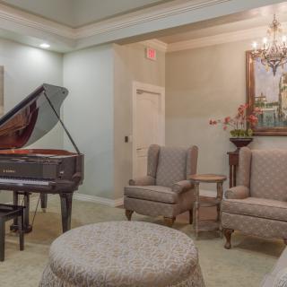 A cozy living room with a grand piano, comfortable seating, and elegant decor.