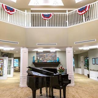 A grand piano in a spacious atrium with patriotic decorations and a balcony.