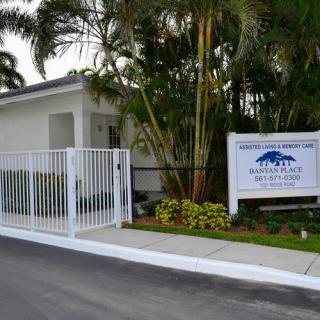 Entrance to a building with a gate and sign surrounded by palm trees.