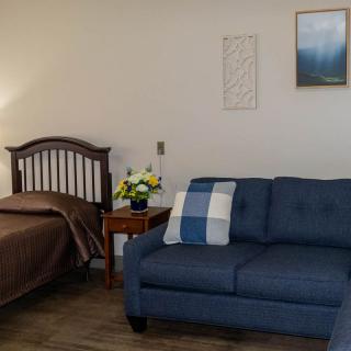 A cozy bedroom with a wooden bed, blue sofa, and decorative elements.