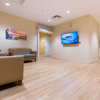 A modern waiting room with comfortable seating and a television display.