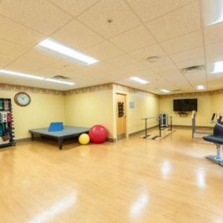 A spacious rehabilitation and fitness room equipped with various exercise equipment and a table for recreational activities.
