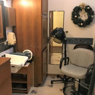 A small hair salon interior with a chair, mirror, and hair dryer.