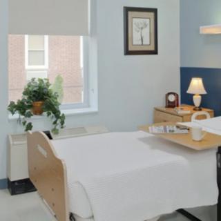 A tidy hospital room with a bed and bedside table.