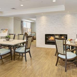 A modern dining area featuring elegant tables and chairs, with a cozy fireplace set into a white brick wall.