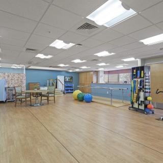 A spacious rehabilitation room equipped with exercise equipment and therapy balls.