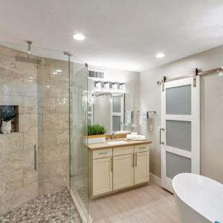 A modern and stylish bathroom with a glass-enclosed shower, freestanding bathtub, and sleek vanity.