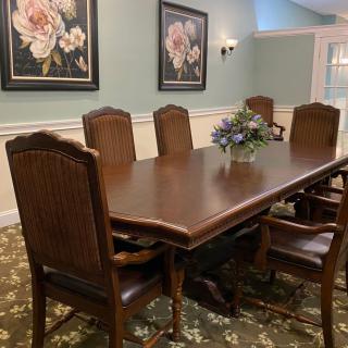 A dining room with a wooden table and chairs, adorned with floral artwork on the walls.