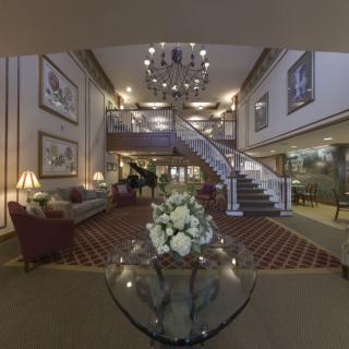 A luxurious hotel lobby featuring a grand staircase, elegant chandelier, and plush seating arrangements.