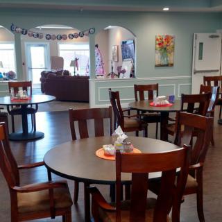 A cozy dining area with neatly arranged tables and chairs, featuring warm decor.