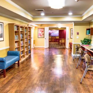 A cozy library room with wooden floors, bookshelves, and seating areas.