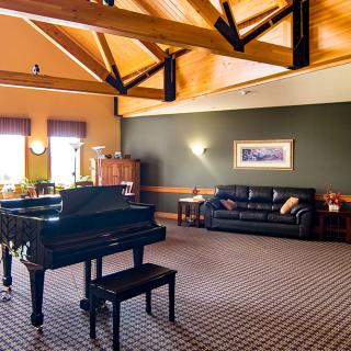 A spacious living room with a grand piano and comfortable seating.