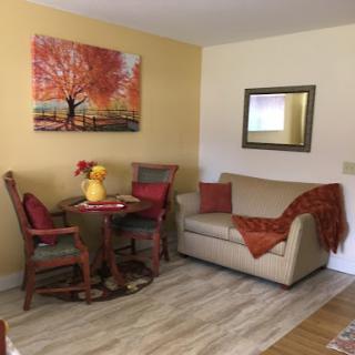 A cozy living space featuring a small dining area and a comfortable sofa, enhanced by warm colors and decorative artwork.