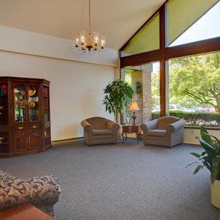 A cozy lobby area with large windows, comfortable seating, and decorative plants.