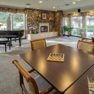 A cozy living room with a fireplace and piano, featuring a table set for board games.