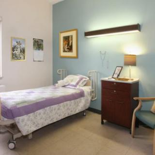 A well-lit hospital room with a single patient bed and basic furnishings.