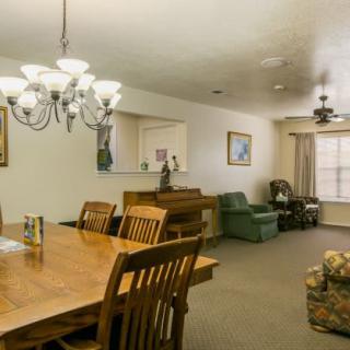 A cozy dining and living area featuring a wooden table with chairs, a chandelier, and comfortable seating.