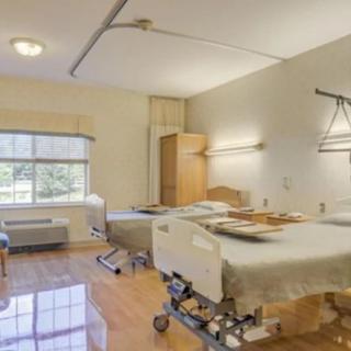 A clean and well-equipped hospital room with two beds and medical equipment.