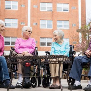 A group of seniors sitting together outside, engaging in conversation.