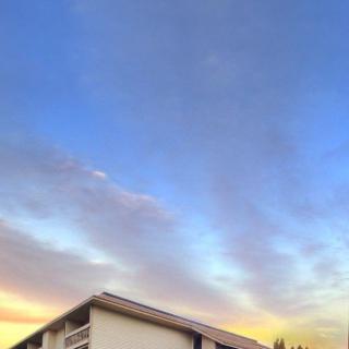 A building under a picturesque sunset sky with wispy clouds.