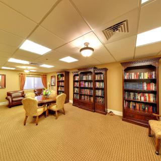 A cozy library room with wooden bookshelves filled with books, a conference table, and comfortable seating.