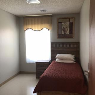 A minimalist bedroom with a single bed, side table, and window.