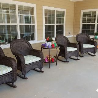 A cozy patio with wicker rocking chairs arranged in a row, accompanied by a small table and decorative items.