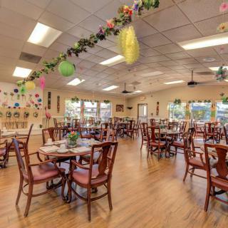 An empty dining room with tables set and decorated ceilings.