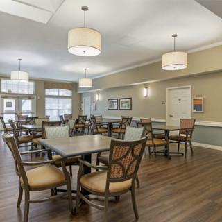 A spacious dining room with wooden tables and chairs, well-lit by modern pendant lights.