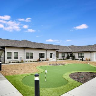 A modern building with a small putting green under a clear blue sky.