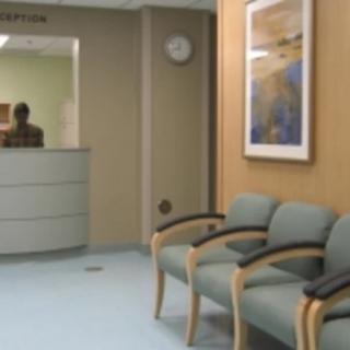 A quiet waiting area with chairs and a reception desk in a clinic or office.