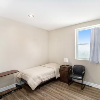 A minimalist bedroom with a single bed and basic furnishings.