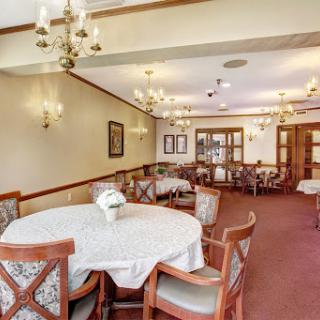 A cozy dining area featuring a round table surrounded by chairs, illuminated by elegant chandeliers.