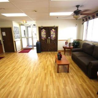 A spacious waiting room with a wooden floor, featuring a sofa and table.