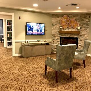 A cozy living room with a television, fireplace, and two armchairs.