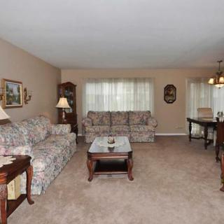 A cozy living room with floral-patterned sofas, a coffee table, and adjoining dining area.