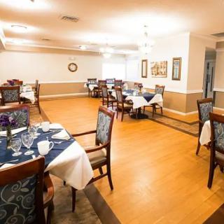 A well-lit dining area with neatly arranged tables and chairs, featuring elegant table settings.