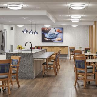 A modern dining and kitchen area with wooden flooring, contemporary furniture, and stylish lighting fixtures.