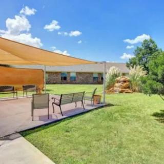 A sunny backyard with a shaded patio and outdoor seating area.