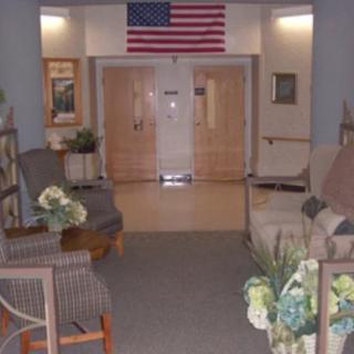 A well-decorated lobby area with comfortable seating, plants, and an American flag above the entrance.