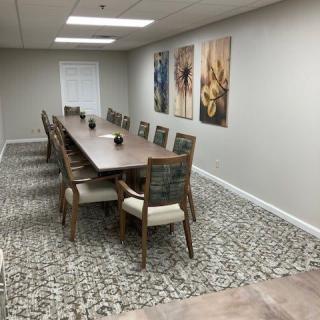 A modern conference room with a long wooden table, surrounded by chairs and adorned with artwork on the walls.