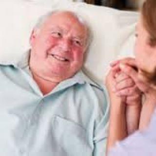 An elderly man smiling while receiving care and support.