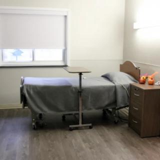 A clean and minimalist hospital room with a bed and bedside table.
