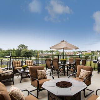 A cozy outdoor patio with comfortable seating, a fire pit, and an umbrella overlooking a scenic landscape.