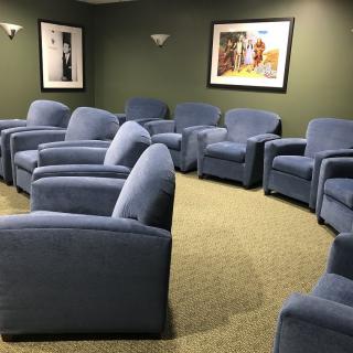 A comfortable waiting room with several blue upholstered chairs arranged in a circular layout.