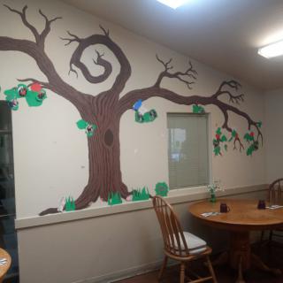 An indoor dining area featuring a mural of a tree with branches extending across the wall.