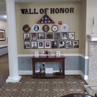 A Wall of Honor displaying military memorabilia and portraits, featuring an American flag in a decorative setting.
