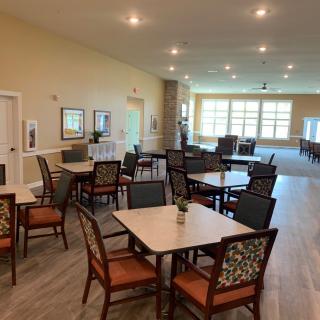 A spacious and well-lit dining area with multiple tables and chairs arranged neatly.