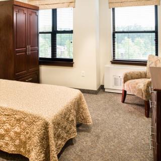 A cozy bedroom with a single bed, wardrobe, and a chair by the window.